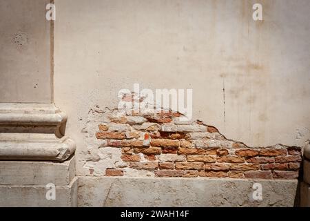 Alte Wand mit Putzputz fällt ab und freiliegender Ziegelstein muss repariert werden. Stockfoto