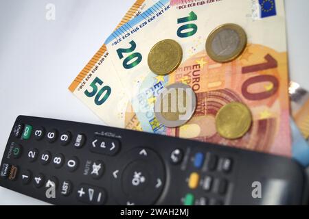 Fernbedienung und Geld, Symbolbild des Pay-TV Stockfoto