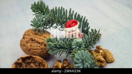 Walnüsse, Tannenzweig und Weihnachtsfigur, symbolisches Weihnachtsbild Stockfoto