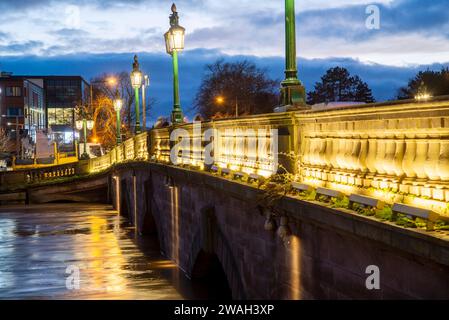 Bei Sonnenuntergang, nach stürmischem, nassem Wetter, beträchtliche Regenwasserbäche, die unter der beleuchteten historischen Brücke, entlang der Severn, nach dem Eingießen passieren Stockfoto