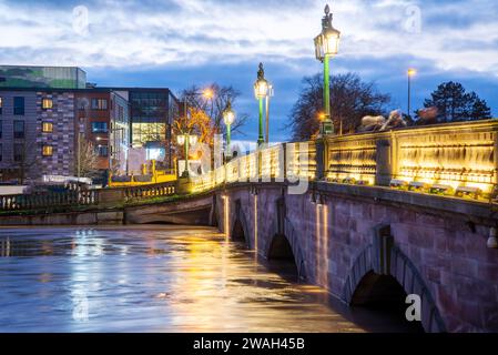 Bei Sonnenuntergang, nach stürmischem, nassem Wetter, beträchtliche Regenwasserbäche, die unter der beleuchteten historischen Brücke, entlang der Severn, nach dem Eingießen passieren Stockfoto