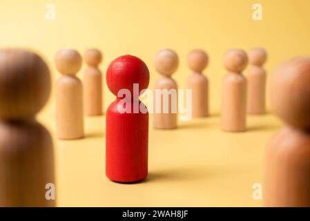 Rote Holzfiguren heben sich von der Menge der Holzfiguren ab. Führungskonzept Stockfoto