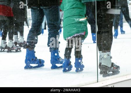 Menschen, die auf Schlittschuhen in der Eislaufarena in der Stadt stehen und das kalte Wetter im Winter genießen Stockfoto