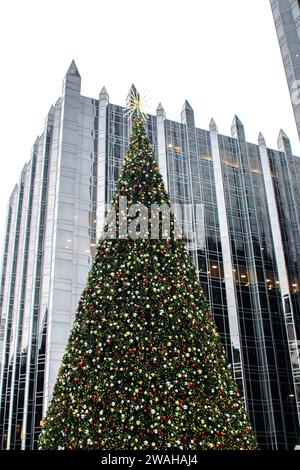 Der Weihnachtsbaum in der Mitte der Eislaufbahn der PPG Arena ist mit dem Pittsburgh Plate Glass Skyscraper im Hintergrund beleuchtet Stockfoto