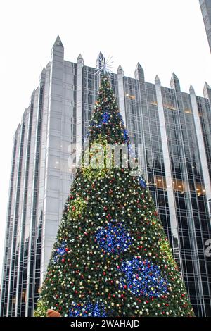 Der Weihnachtsbaum in der Mitte der Eislaufbahn der PPG Arena ist mit dem Pittsburgh Plate Glass Skyscraper im Hintergrund beleuchtet Stockfoto