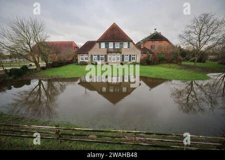 Hagen Grinden, Deutschland. Januar 2024. Wasser steht auf einer Wiese vor einem Bauernhof im kleinen Dorf Hagen-Grinden. Das Dorf Hagen-Grinden bei Bremen war durch die Überschwemmung tagelang von der Außenwelt abgeschnitten. Quelle: Christian Charisius/dpa/Alamy Live News Stockfoto