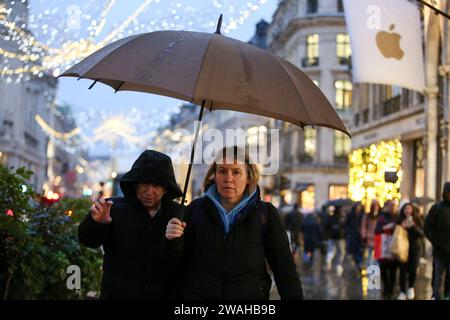 London, Großbritannien. Januar 2024. Käufer schützen sich vor dem Regen unter ihren Regenschirmen in der Oxford Street in London, Großbritannien, 4. Januar 2024. Das Met Office, der nationale Wetterdienst Großbritanniens, gab am Mittwoch eine gelbe Wetterwarnung für starke Regenfälle im Süden Englands von Donnerstag bis Freitag aus. Quelle: Xinhua/Alamy Live News Stockfoto