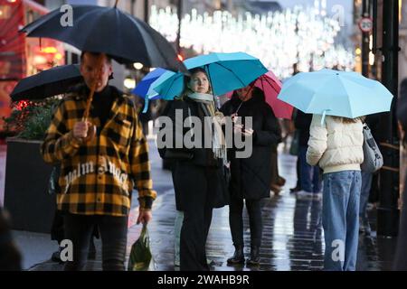 London, Großbritannien. Januar 2024. Käufer schützen sich vor dem Regen unter ihren Regenschirmen in der Oxford Street in London, Großbritannien, 4. Januar 2024. Das Met Office, der nationale Wetterdienst Großbritanniens, gab am Mittwoch eine gelbe Wetterwarnung für starke Regenfälle im Süden Englands von Donnerstag bis Freitag aus. Quelle: Xinhua/Alamy Live News Stockfoto