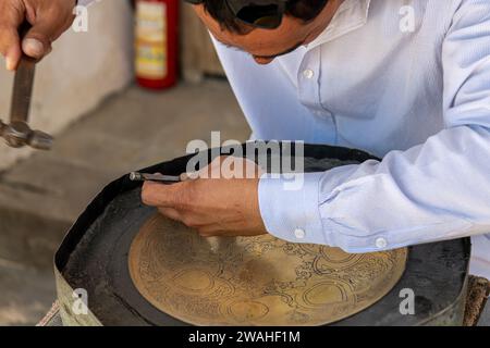 27. JUNI 2023, BUCHARA, USBEKISTAN: Der Meister, der die Metallarbeiten für den Verkauf als Souvenir macht Stockfoto