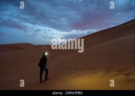 Fotograf mit Scheinwerfer bei Sonnenaufgang in der Wüste, Dünen, Erg Chebbi, Sahara, Merzouga, Marokko Stockfoto