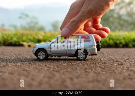 Konzept für Outdoor-Aktivitäten mit Kinderspielzeug. Foto eines Spielzeugautos, das von Hand gehalten wird. Nach einigen Änderungen. Stockfoto