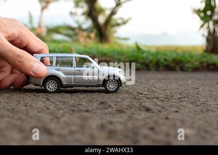 Konzept für Outdoor-Aktivitäten mit Kinderspielzeug. Foto eines Spielzeugautos, das von Hand gehalten wird. Nach einigen Änderungen. Stockfoto