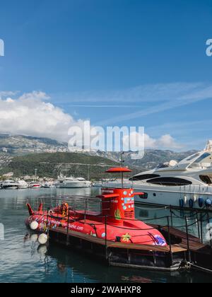 Budva, Montenegro - 17. august 2023: Rotes Exkursions-U-Boot liegt am Pier vor der Kulisse der Berge vor Stockfoto