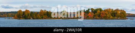 Panorama einer typisch schwedischen Insel in der Stockholmer Grafschaft, mit Herbstfarben. Rote, orange und grüne Blätter, bewölkter Himmel. Stockfoto