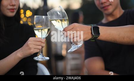 Foto eines jungen Paares, das Champagner auf einem verschwommenen nächtlichen Stadtlicht-Hintergrund toast. Stockfoto