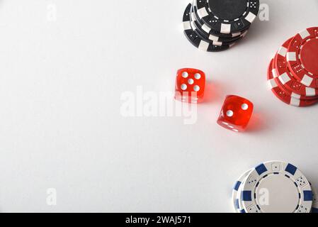 Spielhintergrund mit farbigen Chips zum Wetten und zwei roten Würfeln auf weißem Tisch. Draufsicht. Stockfoto