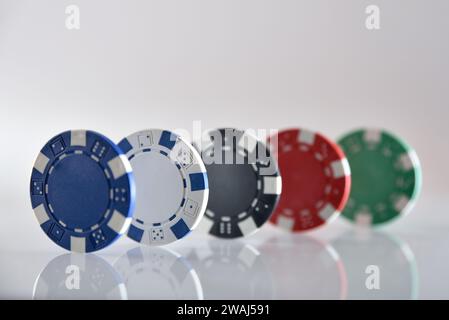 Detail von fünf verschiedenen farbigen Spielchips aus Plastik in Linie auf weißem isoliertem Hintergrund. Vorderansicht. Stockfoto