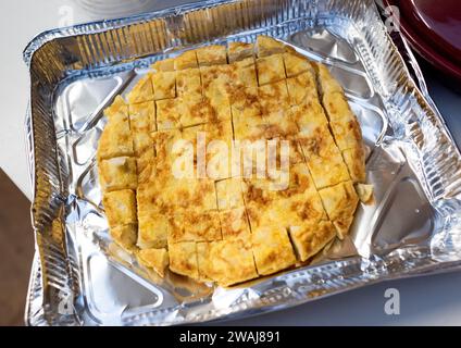 Spanisches Omelett mit Kartoffeln und Zwiebeln, vorgeschnitten und verzehrfertig in Einwegtablett Stockfoto