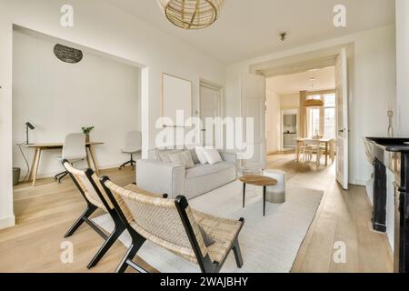 Stühle und Sofa im geräumigen Wohnzimmer des modernen Apartments mit Esszimmer durch offene Tür Stockfoto