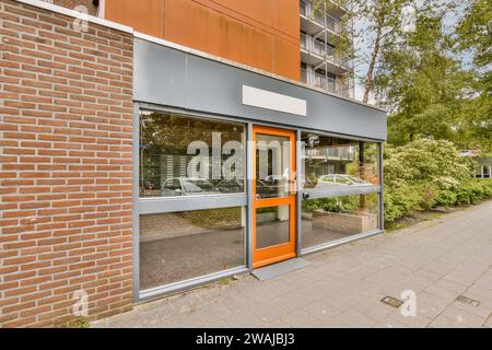 Glastür und Fenster am Vordereingang des modernen Gebäudes mit Bäumen und Backsteinmauer Stockfoto