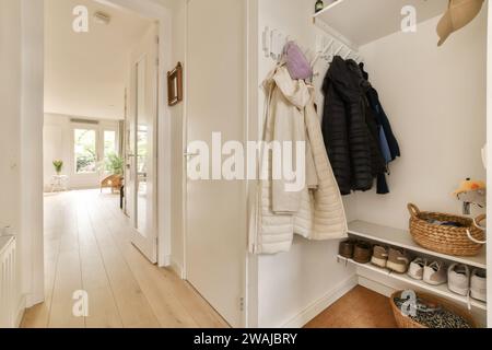 Innenraum des leeren Flurs mit Mänteln an der Wand und Schuhen auf einem Regal in einem modernen weißen Apartment Stockfoto