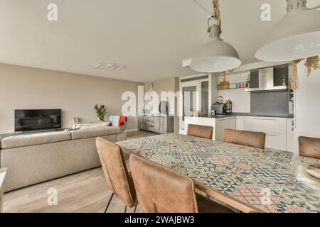 Holztisch und -Stühle im modernen Esszimmer des luxuriösen Apartments mit Wohnzimmer und Küche im Hintergrund Stockfoto