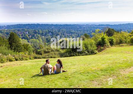 Leute sitzen auf dem Gras am Reigate Hill Aussichtspunkt, North Downs Way, Surrey, England Stockfoto