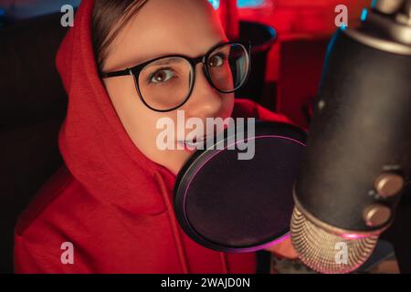 Eine Frau sitzt vor einem Mikrofon und bereit zur Aufnahme. Stockfoto