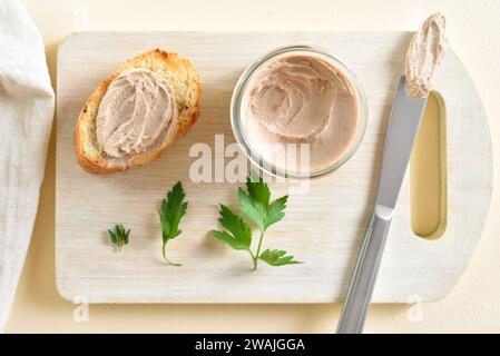 Hühnerleberpastete auf Holzschneidebrett auf hellem Hintergrund. Draufsicht, flach Stockfoto