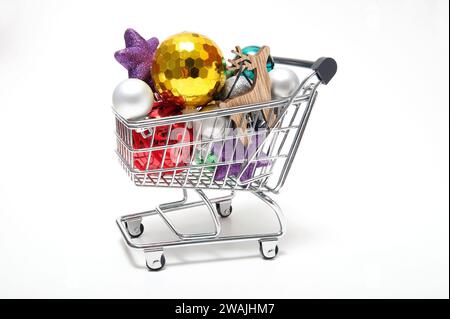 weihnachtskugeln im Miniatur-Supermarktwagen auf weißem Hintergrund Stockfoto
