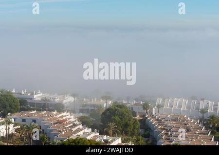 AGUADULCE, SPANIEN - 12. DEZEMBER 2023 Nebel hängt über einer Küstenstadt in Spanien, Blick auf die Promenade, den Küstenstreifen und das Mittelmeer in der Andalu Stockfoto