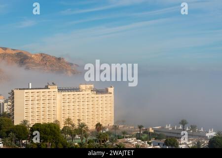 AGUADULCE, SPANIEN - 12. DEZEMBER 2023 Nebel hängt über einer Küstenstadt in Spanien, Blick auf die Promenade, den Küstenstreifen und das Mittelmeer in der Andalu Stockfoto