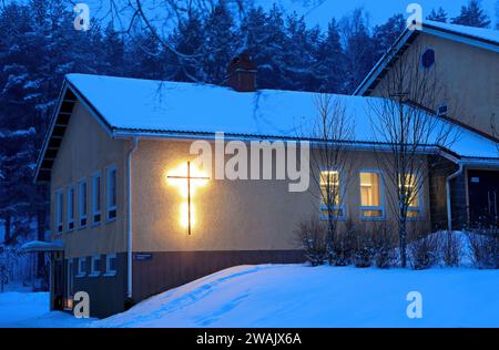 Die Pfarrhalle in der blauen Dämmerung. Schild an der Wand „Friedhofbüro“ Stockfoto