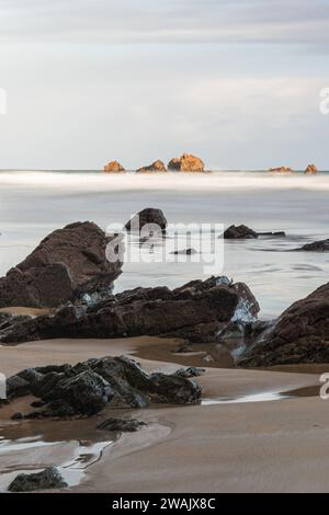 Ruhe an einem Wintermorgen in Playa del Aguilar in Asturien, Spanien. Ein Strand mit einem Naturdenkmal in der Mitte. Der Felsen von Playa del Aguila Stockfoto