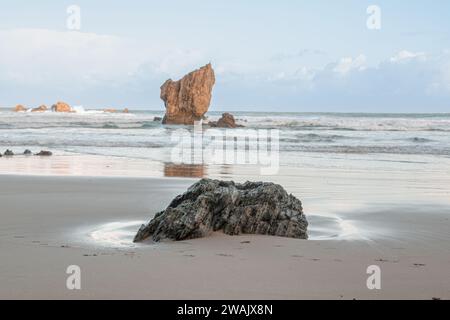 Ruhe an einem Wintermorgen in Playa del Aguilar in Asturien, Spanien. Ein Strand mit einem Naturdenkmal in der Mitte. Der Felsen von Playa del Aguila Stockfoto