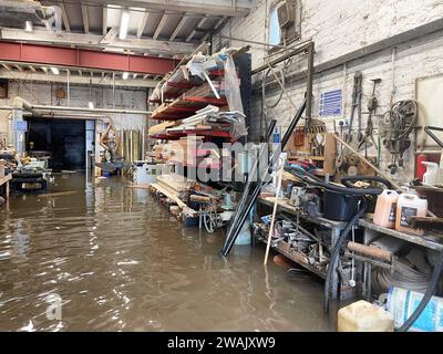 Hochwasser in Kirk and Bill's, einer Möbelwerkstatt in Newark-on-Trent, Nottinghamshire. Wasser ist durch die Dielen und Abflüsse aufgrund der Überschwemmung durch Sturm Henk gestiegen, die die Werkstatt überschwemmt hat. Bilddatum: Freitag, 5. Januar 2024. Stockfoto