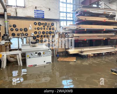 Hochwasser in Kirk and Bill's, einer Möbelwerkstatt in Newark-on-Trent, Nottinghamshire. Wasser ist durch die Dielen und Abflüsse aufgrund der Überschwemmung durch Sturm Henk gestiegen, die die Werkstatt überschwemmt hat. Bilddatum: Freitag, 5. Januar 2024. Stockfoto