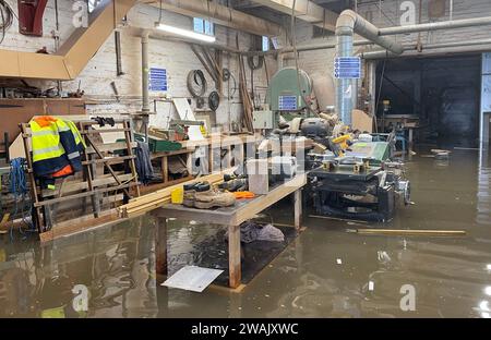 Hochwasser in Kirk and Bill's, einer Möbelwerkstatt in Newark-on-Trent, Nottinghamshire. Wasser ist durch die Dielen und Abflüsse aufgrund der Überschwemmung durch Sturm Henk gestiegen, die die Werkstatt überschwemmt hat. Bilddatum: Freitag, 5. Januar 2024. Stockfoto