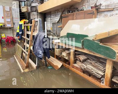 Hochwasser in Kirk and Bill's, einer Möbelwerkstatt in Newark-on-Trent, Nottinghamshire. Wasser ist durch die Dielen und Abflüsse aufgrund der Überschwemmung durch Sturm Henk gestiegen, die die Werkstatt überschwemmt hat. Bilddatum: Freitag, 5. Januar 2024. Stockfoto