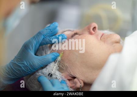 Die Durchführung von Gesichtsinjektionen in einer ästhetischen Klinik. Stockfoto