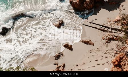 Ein Blick aus der Vogelperspektive auf das ruhige Meer und die Spuren im Sand am Strand Cala Saladeta, Ibiza, Spanien Stockfoto