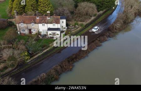 Ein Auto fährt durch das Hochwasser des Cuckmere River in Alfriston, East Sussex. Die Auswirkungen von Oberflächenwasser- und Flusspflutungen werden in Teilen Englands nach starken Regenfällen weiterhin „erheblich“ sein, warnten Experten. Bilddatum: Freitag, 5. Januar 2024. Stockfoto