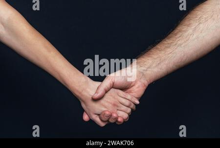 Die Hand einer Frau hält die Hand eines Mannes. Hände auf schwarzem Hintergrund halten Stockfoto