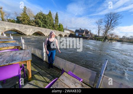 Fordingbridge, Hampshire, UK, 5. Januar 2024: Wetter: Strahlender Sonnenschein und blauer Himmel Freitag nach der Sintflut am Donnerstag im Süden Englands. Am George Inn, das direkt am Rande des Flusses Avon liegt, werden improvisierte Hochwasserschutzanlagen das Wasser am oberen Ende der Terrasse ablenken und das Gelände vor Überschwemmungsschäden schützen. Die Besitzerin Caroline Roylance untersucht den Tatort. Der Wasserstand könnte in den nächsten Tagen weiter steigen, da die Regenfälle von der Salisbury Plain flussaufwärts abfließen. Paul Biggins/Alamy Live News Stockfoto