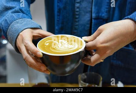 PU'er, chinesische Provinz Yunnan. Januar 2024. Ein Aussteller zeigt eine Tasse Kaffee während der China (Pu'er) International Coffee Expo in Pu'er, südwestchinesische Provinz Yunnan, 5. Januar 2024. Mehr als 200 Unternehmen nahmen vom 5. Bis 7. Januar an der China (Pu'er) International Coffee Expo Teil. Quelle: Xiong Xuanang/Xinhua/Alamy Live News Stockfoto