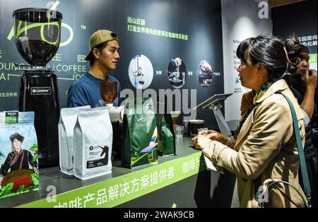 PU'er, chinesische Provinz Yunnan. Januar 2024. Ein Aussteller (L) stellt einem Kunden Kaffeeprodukte während der China (Pu'er) International Coffee Expo in Pu'er, südwestchinesischer Provinz Yunnan, am 5. Januar 2024 vor. Mehr als 200 Unternehmen nahmen vom 5. Bis 7. Januar an der China (Pu'er) International Coffee Expo Teil. Quelle: Xiong Xuanang/Xinhua/Alamy Live News Stockfoto