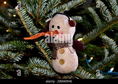 Ein Schneemannschmuck aus Filz mit einer langen Karottennase auf einem Weihnachtsbaum. Stockfoto
