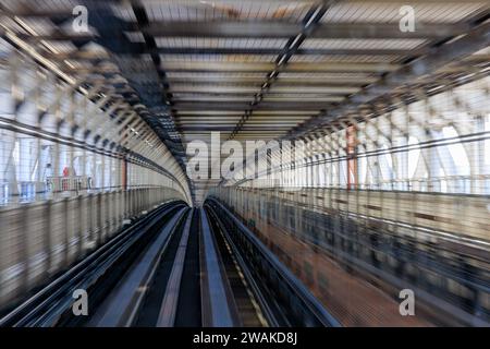 Großartige Bewegung beim Blick vom Vordersitz der fahrerlosen yurikamome-Linie, die die Regenbogenbrücke im Hafen von tokio überquert Stockfoto