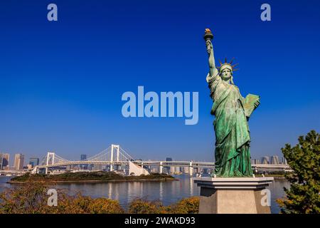 Landschaftsbild der tokyo Freiheitsstatue im Vordergrund vor der Regenbogenbrücke und der Hafenpromenade von tokio Stockfoto