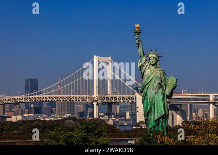 Landschaftsbild der tokyo Freiheitsstatue im Vordergrund vor der Regenbogenbrücke und der Hafenpromenade von tokio Stockfoto